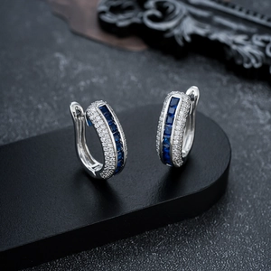 Silver huggie earrings with central square blue stone and micro pavé zircon accents