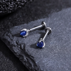 Detailed close-up of blue zircon dragon claw stud earring on dark stone surface