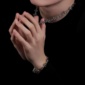 Close-up of vintage silver cross necklace and bracelet set with gothic floral motifs