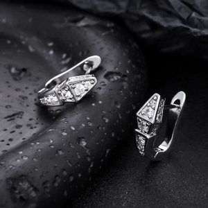 Macro shot of silver geometric zircon earrings on a black textured background