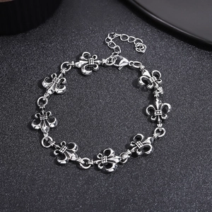 Detail of vintage silver Fleur-de-lis bracelet with lobster clasp on leather background