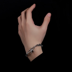 Detail of silver thorn punk bracelet featuring double-layered chain on a black background