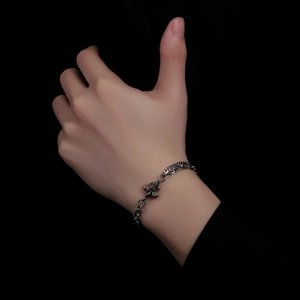Nahaufnahme eines Vintage-Gothic-Cross-Armbands mit zweilagiger Kette und Lilien-Anhänger