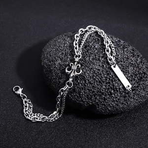Detail eines silbernen zweilagigen Armbands mit Lilienanhänger und ID-Tag auf schwarzem Fels