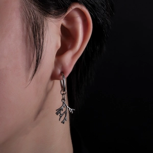 Silver stainless steel leaf branch drop earring on model with minimalist black background