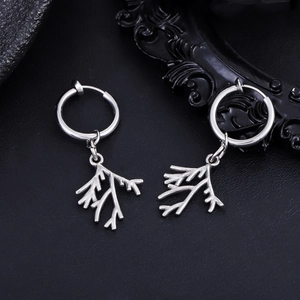 Detailed view of silver stainless steel leaf branch drop earrings on a dark textured surface