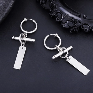 Close-up of polished silver titanium steel tag clip earrings on a black leather surface