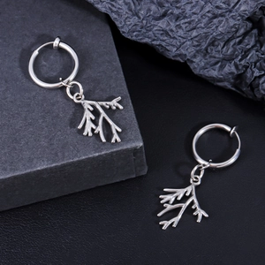 Detailed view of silver stainless steel leaf branch drop earrings on elegant black packaging