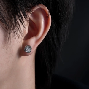 Close-up of square zircon halo stud earring in silver on model's ear with dark background