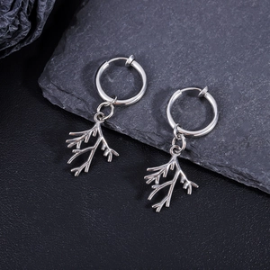 Polished silver leaf pendant earrings on gray rock, showcasing cool metallic texture