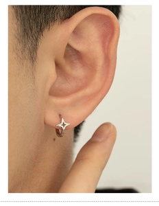 Close-up of a silver star hoop earring on ear showing minimalist four-pointed star detail