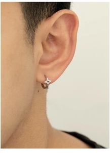 Close-up of silver star hoop earring on ear showing polished metallic texture and star detail