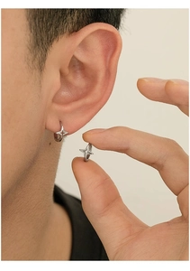 Detailed close-up of a silver four-pointed star hoop earring worn by a model