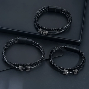 Detailed close-up of three black braided leather bracelets with black magnetic clasps