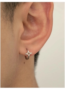 Close-up of silver star hoop earring worn on ear showing detailed four-point star pendant