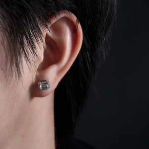 Macro shot of a square emerald-cut zircon earring on ear with a halo of small crystals