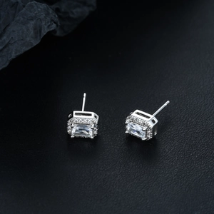 Macro shot of silver halo stud earrings featuring a rectangular cubic zirconia with side stones
