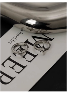 Detailed view of silver star drop earrings featuring a four-pointed star on a minimalist card