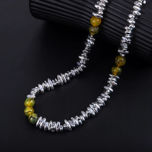Macro shot of silver metal beads and green agate stone beads on a sleek necklace
