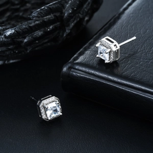 Macro shot of silver square halo earrings with sparkling cubic zirconia on black leather