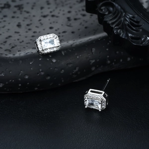 Radiant silver rectangular zircon stud earrings with micro-pave halo on dark rock