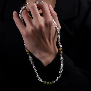 Minimalist black gallstone necklace with green beads on a black suit jacket for men
