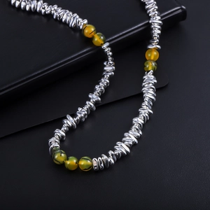 Detailed view of silver irregular metal beads and yellow translucent stones on a necklace