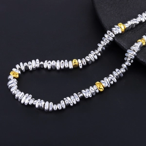 Macro shot of irregular silver and gold beaded necklace with raw black stone decor
