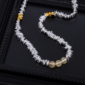 Detail of silver beads and yellow crystal beads on a minimalist luxury necklace