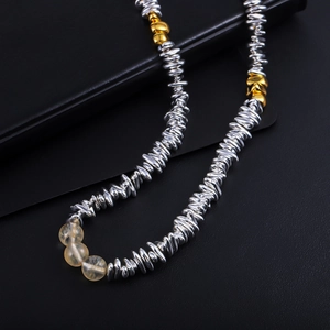 Detail of silver metallic beads and translucent yellow crystals on a black leather surface