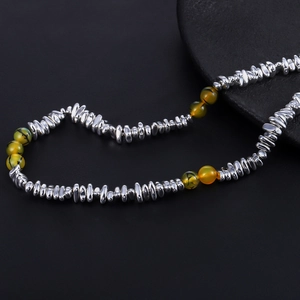 Macro shot of irregular polished silver metal beads with translucent yellow agate beads
