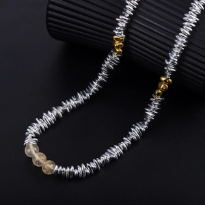Macro detail of textured silver spiral beads and yellow crystal beads on a stylish necklace