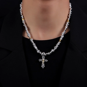 Detail of cross pendant necklace with textured silver disks and metallic bead accents