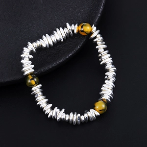 Detail of silver disc beads bracelet with three tiger eye stone accents on black background