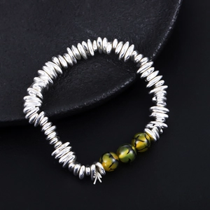 Detailed macro shot of silver beads and green hematite stone bracelet on black display