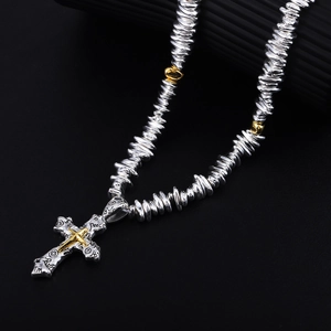 Detail showing cross pendant with gold star and silver textured chain in industrial style