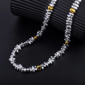Macro detail of high-shine irregular silver beads with gold accents on black texture
