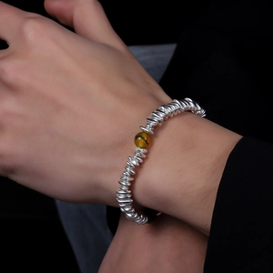 Detail of beaded bracelet with silver spacer beads and amber-colored stone on wrist