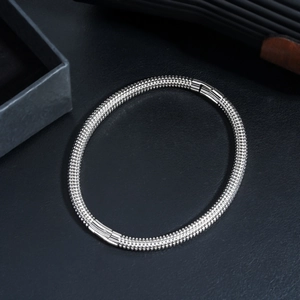 Detailed close-up of textured stainless steel multi-layer bracelet on black leather base