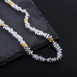 Macro detail of silver and gold hematite beads on a textured grey stone surface