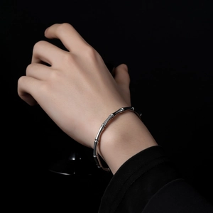 Minimalist silver bamboo joint bangle in stainless steel worn on a model's wrist