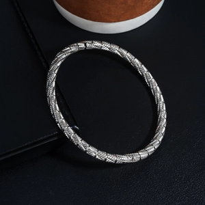 Detail of silver stainless steel cuff bracelet with woven texture on black leather