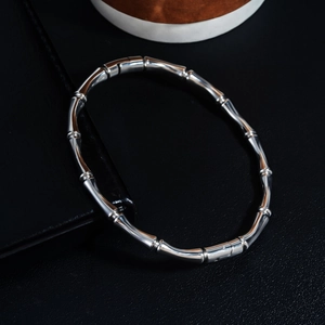 Macro shot of silver bamboo joint bangle with polished stainless steel finish on black leather