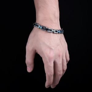 Detail of silver link chain bracelet with navy blue accents on model's wrist