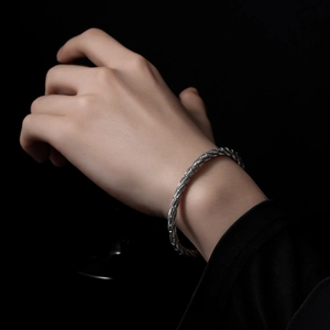 Unisex silver stainless steel bracelet featuring a detailed braided metal texture on black