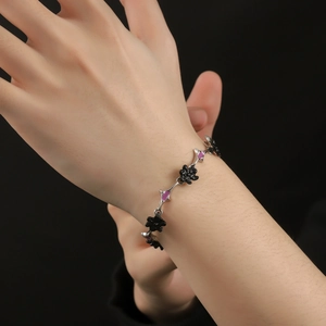 Silver chain bracelet with black floral elements and pink-purple accents on wrist