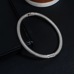 Macro detail of silver stainless steel screw thread bangle with mechanical texture
