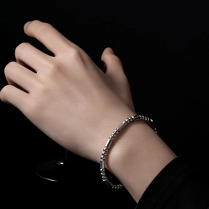 Détail d'un bracelet minimaliste en perles d'acier inoxydable porté sur fond noir sombre