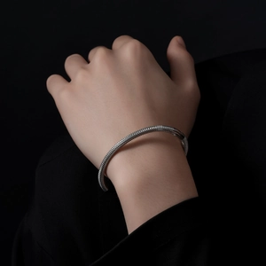 Close-up of silver stainless steel cuff bracelet featuring intricate woven mesh texture