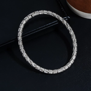 Macro view of silver stainless steel bracelet featuring intricate woven texture and buckle